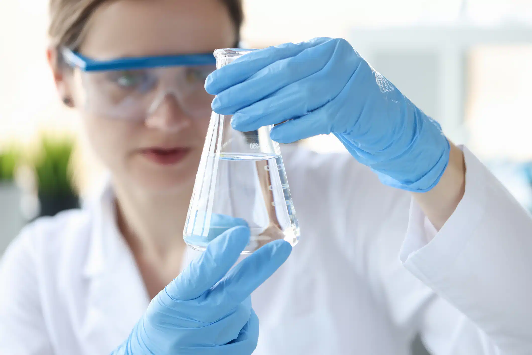 Woman scientist holding flask with transparent liquid in her hands closeup Bulk Water For A Fill
